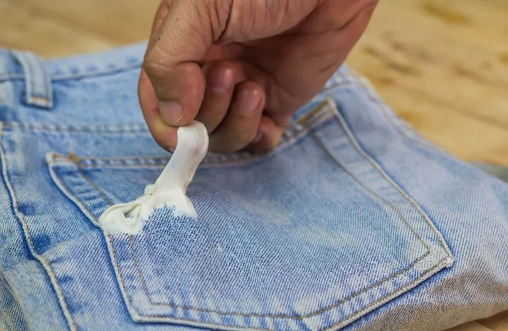 Hand entfernt Kaugummi von Jeans